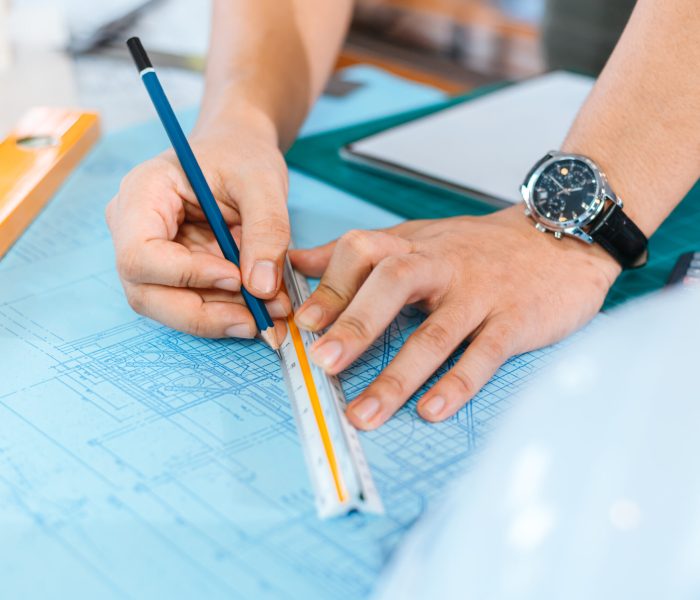 engineers holding a pen pointing to a building and drawing out